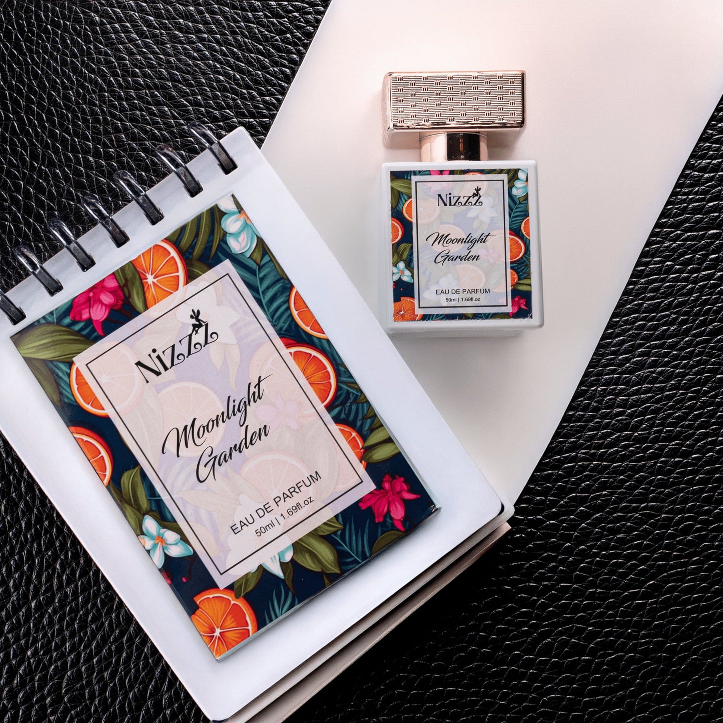 Nizzz Moonlight Garden Eau de Parfum bottle and notebook with floral citrus design on black leather