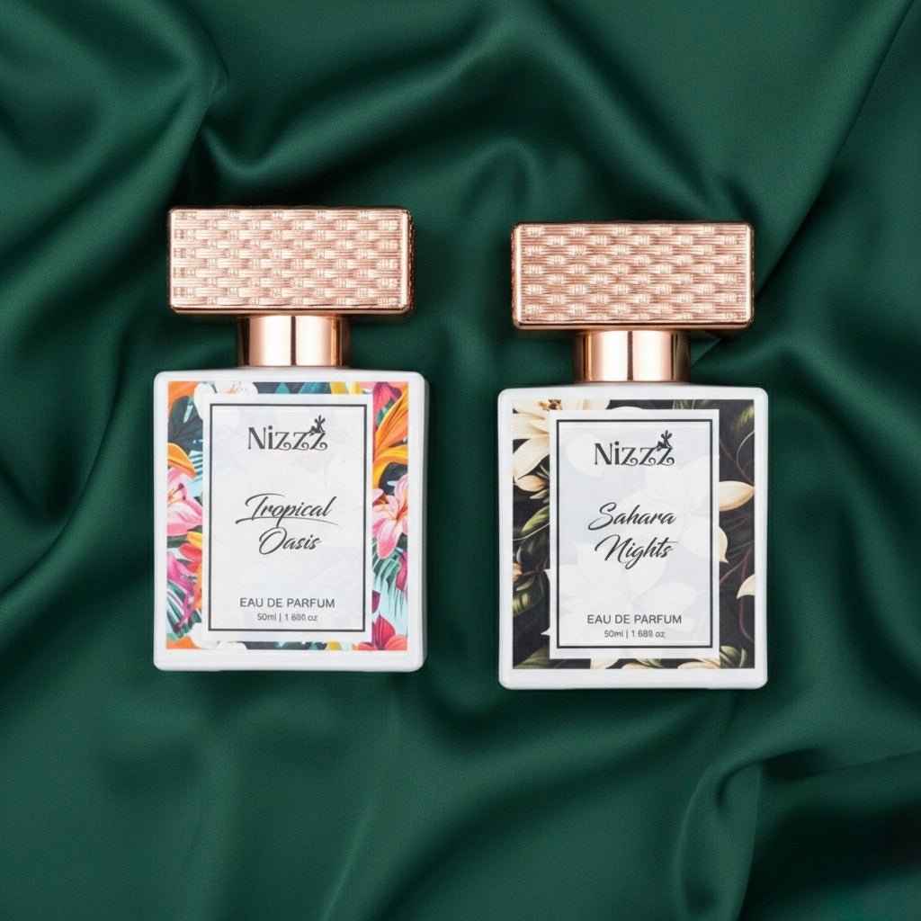 Two floral perfume bottles, Tropical Oasis and Sahara Nights, with rose gold caps on green fabric