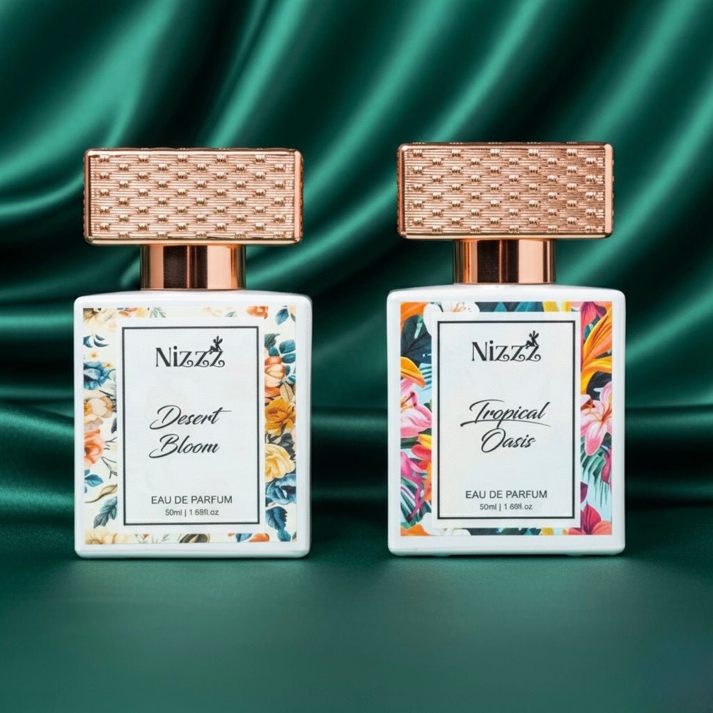Two floral perfume bottles, Desert Bloom and Tropical Oasis, with rose gold caps on green satin background